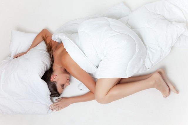 Žena prikrytá bielou pernou v posteli